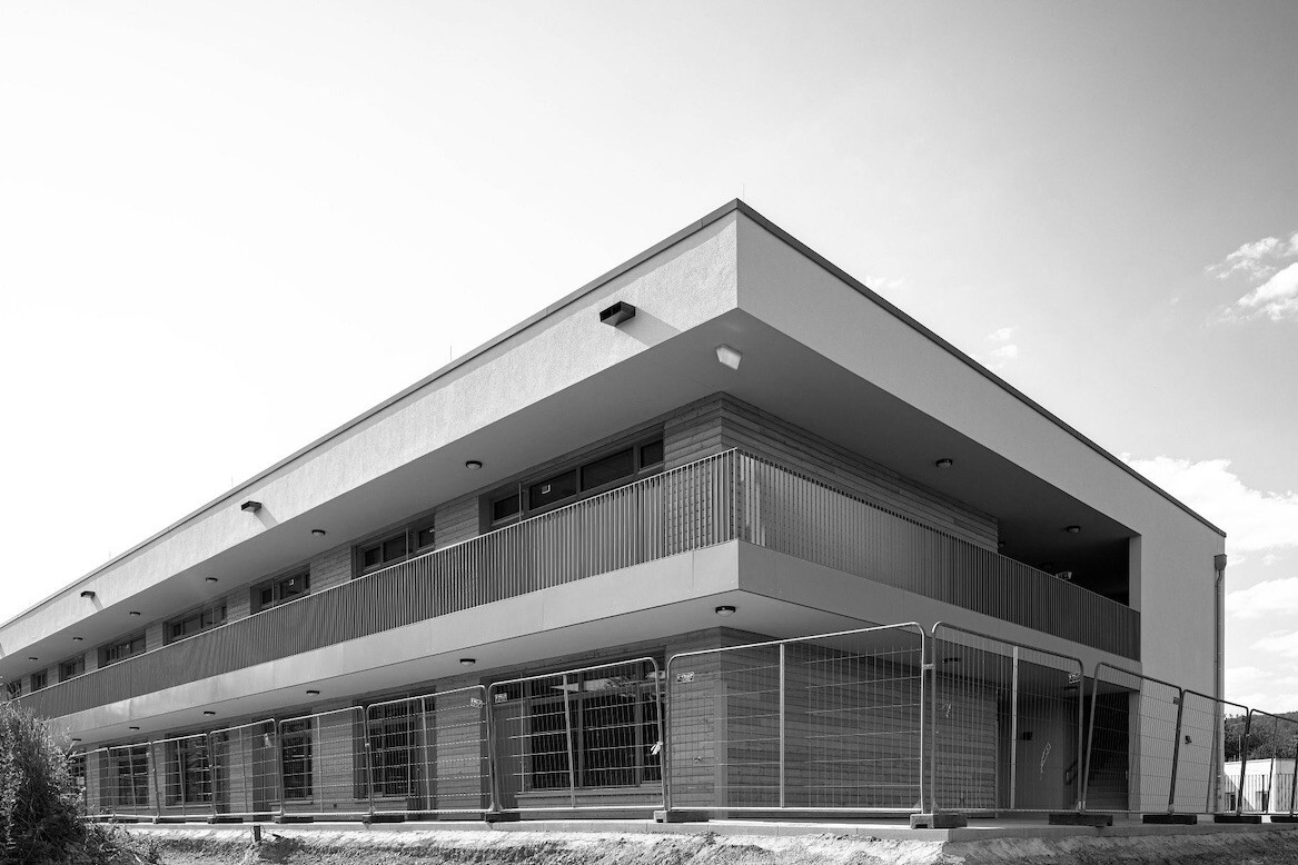 Ein Bild das den Neubau einer Kindertagesstätte in Holz-Hybrid Bauweise vor einem blauen Himmel zeigt.
